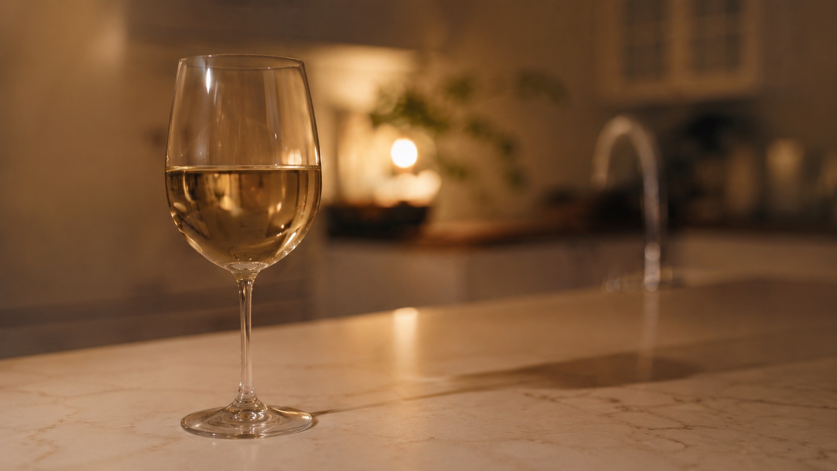 Een glas witte wijn op het aanrecht in de avond