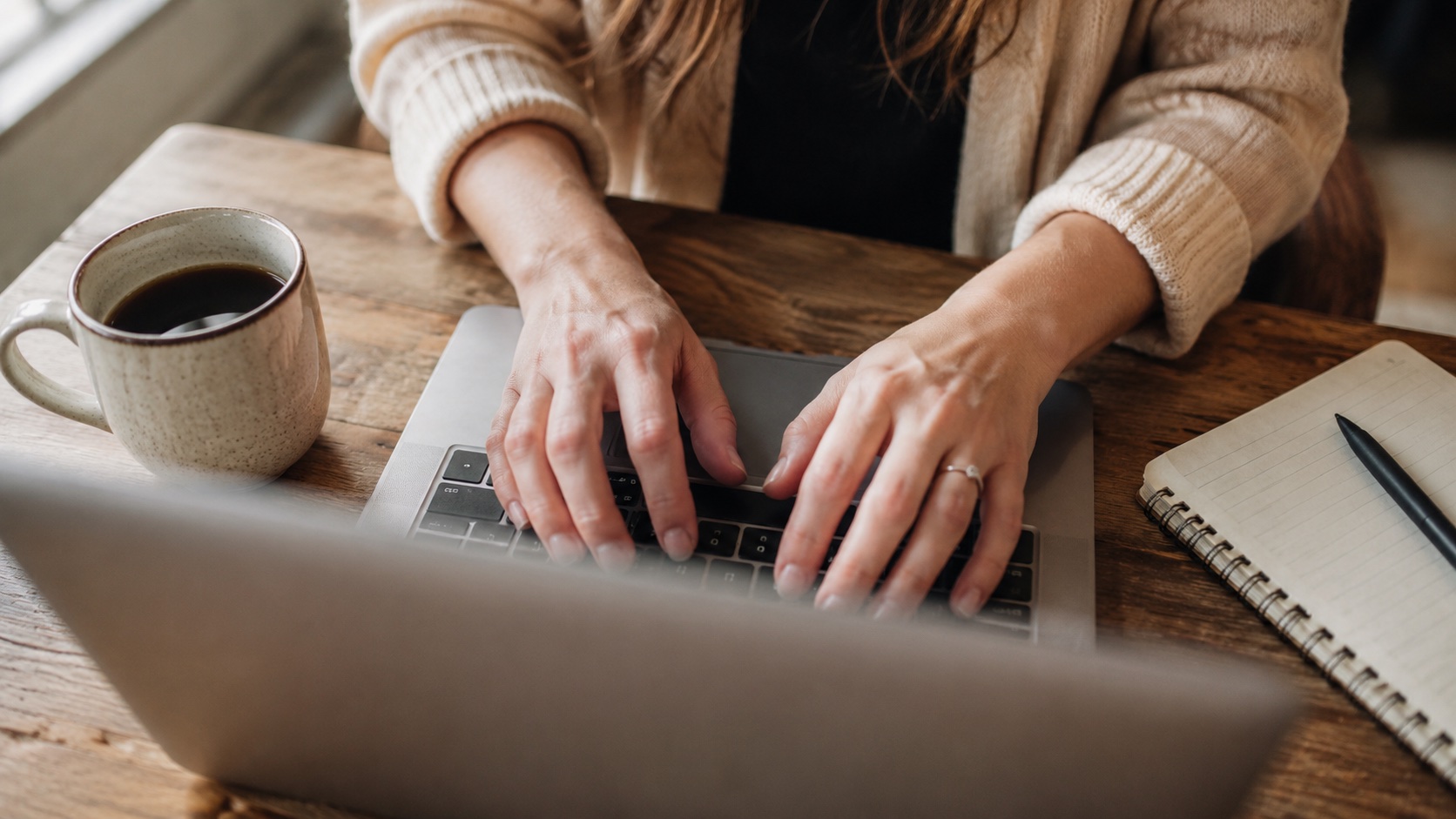 Babyposter online bestellen: close-up van handen op een laptop-toetsenbord met koffie