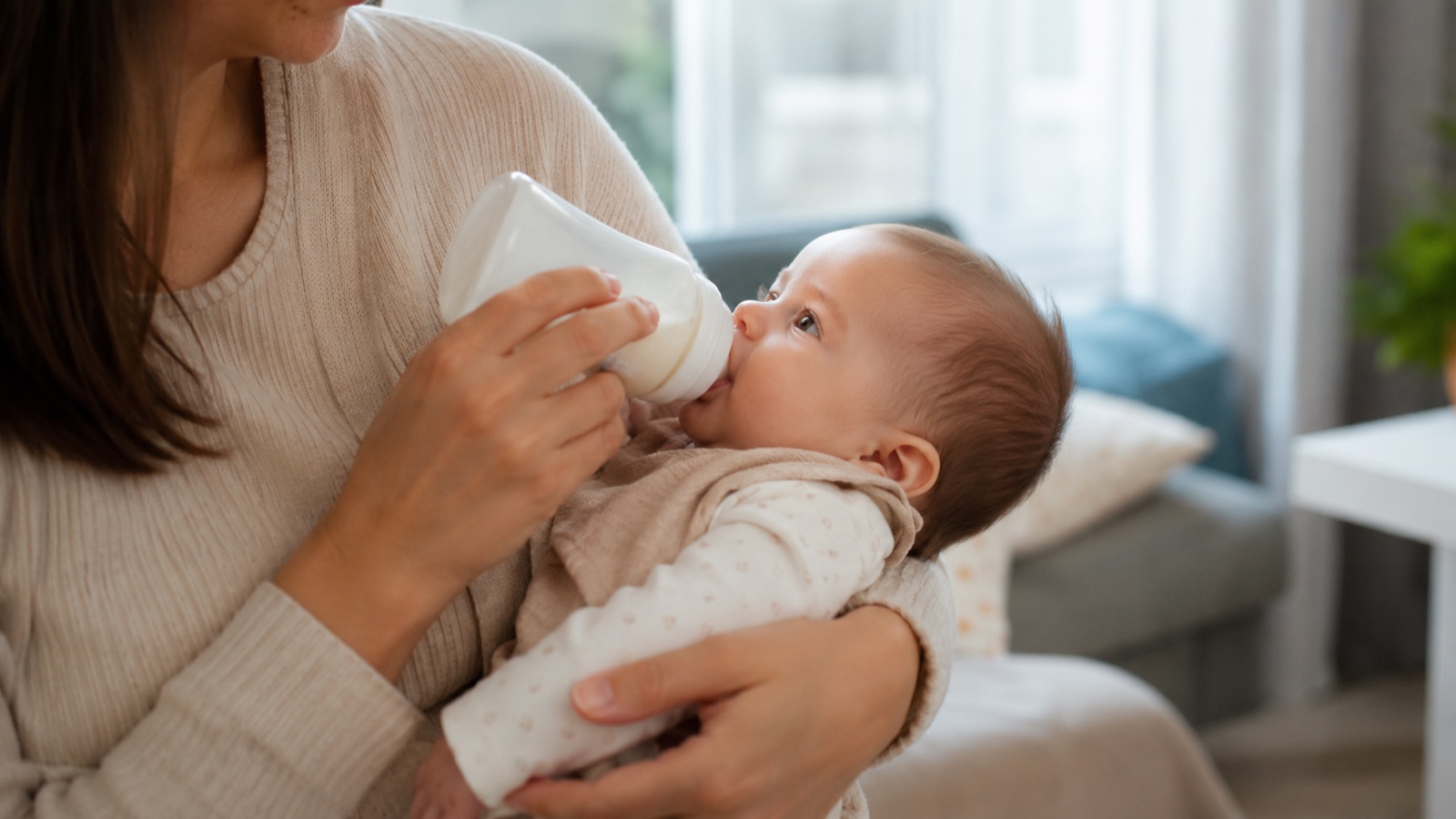 Vader geeft zijn baby liefdevol de fles in een warme woonkamer
